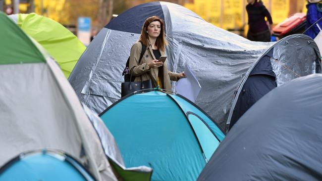 A pedestrian passes through the tent camp set up opposite the Reserve Bank of Australia at Martin Place. Picture: AAP Image/Joel Carrett.