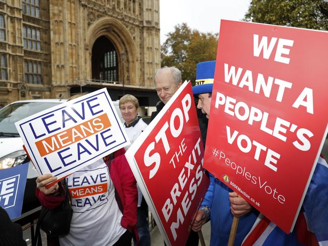 Pro and anti Brexit protesters with their placards, mingle outside the Palace of Westminster in central London on November 15, 2018, as inside lawmakers discuss the draft withdrawal agreement negotiated between the European Union and the United Kingdom. (Photo by Adrian DENNIS / AFP)