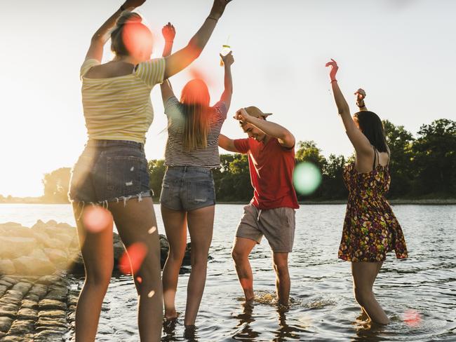 Group of happy friends having fun in a river at sunset. Picture: Getty Images