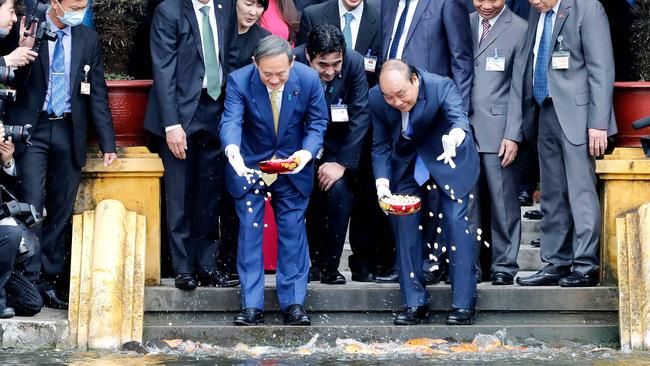 Yoshihide Suga and Nguyen Xuan Phuc feed the fish at the Presidential Palace in Hanoi on Monday. Picture: AFP