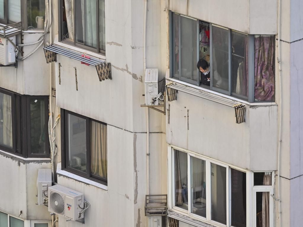 A woman looks out of an apartment during a lockdown in the Jing'an district in Shanghai. Picture: AFP