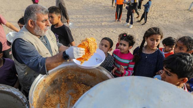 Citizens in Rafah line up to receive food cooked and distributed for free before breaking the fast during Ramadan on Saturday. Picture: Getty Images