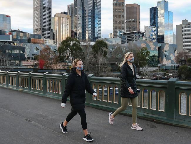 The effects of a stage 4 lockdown are evident as the streets of Melbourne's CBD resemble at times a ghost town. Two women walk across Princes Bridge. Picture : Ian Currie