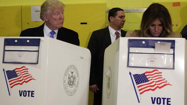 Mr Trump sneaks a peek at his wife’s ballot. Picture: AP