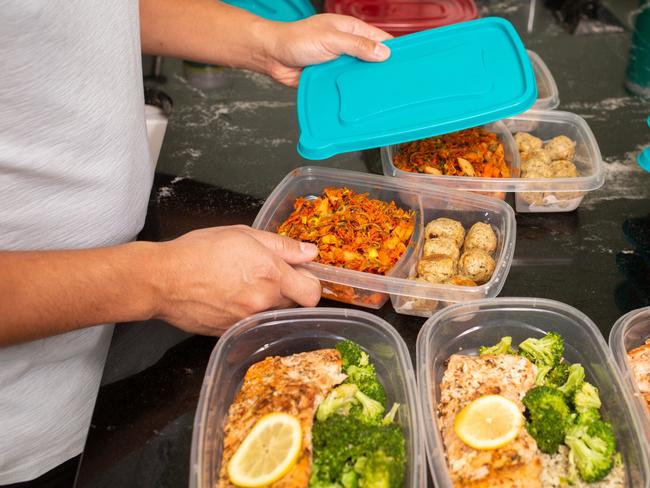 Filipino Man putting away meal prep containers Salmon and Chicken Meat Ball Meal Preps