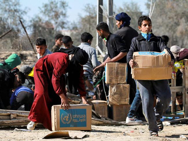 A boy walks with a humanitarian aid package provide by the United Nations Relief and Works Agency for Palestine Refugees (UNRWA) in al-Shoka, east of Rafah in the southern Gaza Strip on January 21, 2025 following a ceasefire deal in the war between Israel and Hamas in the Palestinian territory. (Photo by Bashar TALEB / AFP)