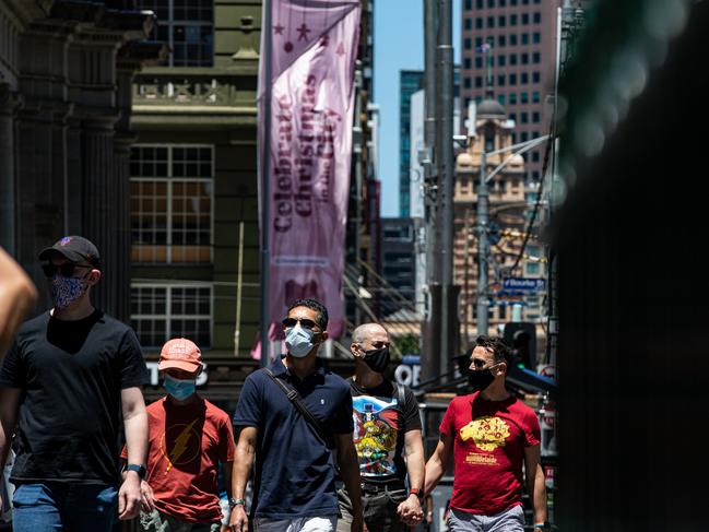 MELBOURNE, AUSTRALIA - DECEMBER 24: People wear a face mask as they walk along Elizabeth Street on December 24, 2021 in Melbourne, Australia. Victoria has reintroduced rules for masks to be worn in indoor settings, as COVID-19 case numbers continue to rise.  From 11:59pm on Thursday 23 December, all Victorians aged 8 and up are required to wear a mask in all non-residential indoor settings. Masks must also be worn while moving around at major events attracting at least 30,000 people, but can be taken off by patrons while sitting down. (Photo by Diego Fedele/Getty Images)