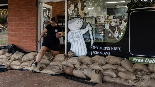 A person walks over sandbags as they are placed around a store to protect it from floodwater in Rochester. Picture: Getty Images