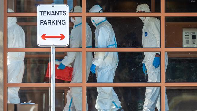 Officials in hazmat suits enter the Flemington public housing towers to drop off food to residents. Picture: Jake Nowakowski