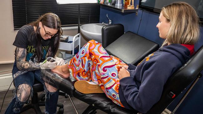 Schoolie Kalahni Bissi getting a tattoo by tattoo artist Arian at Victor Tattoo and Body Piercing Chris Causby. Picture: Tom Huntley