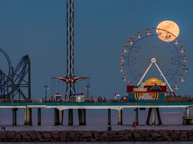Moonrise at the Pier ... The Full Moon glows a soothing yellow as it rises over the Galveston Island Historic Pleasure Pier in Texas, USA, almost appearing to hitch a ride on the ferris wheel. Picture: Sergio Garcia, Insight Astronomy Photographer of the Year Our Moon 2016 Highly Commended