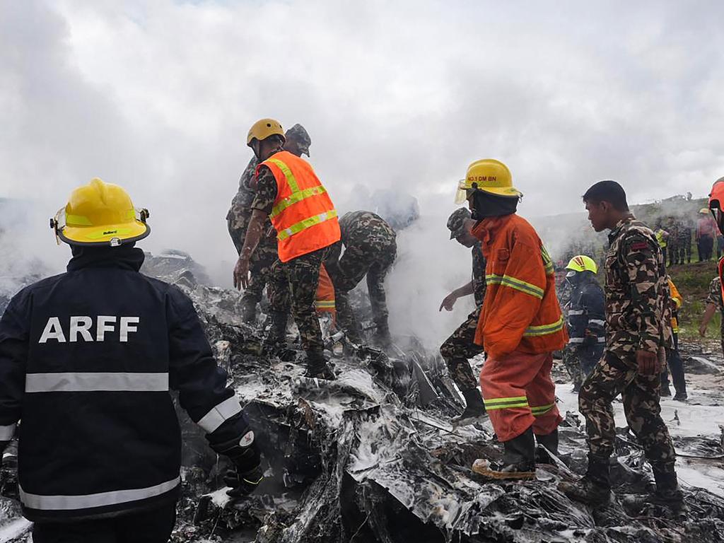 Rescuers and army personnel stand at the site after a Saurya Airlines' plane crashed during takeoff at Tribhuvan International Airport in Kathmandu. Picture: AFP