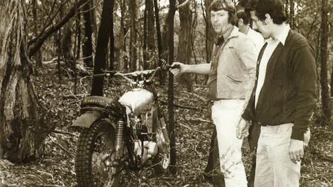 Doug (holding the motorbike handlebar) shows police where he hid his getaway bike in the bush during his re-enactment of the Warburton holdup six months later.  Incredibly, the Kawasaki started straight away although his minder, Sen-Det John Kapetanovski, wasn't about to let him take it for a spin. 