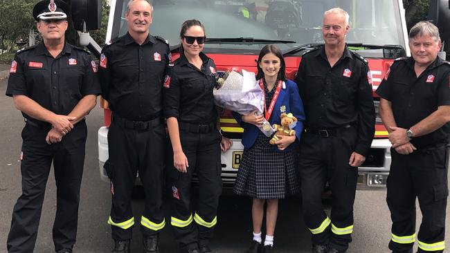 Samantha 'Sammy' Collins, 11, with NSW Fire and Rescue Zone Commander Kel McNamara (in cap) and firefighters from the Dee Why brigade – Michael Long, Narelle Hunter, John Wright and Paul Brierley during their visit to Narraweena. Picture: Jim O'Rourke