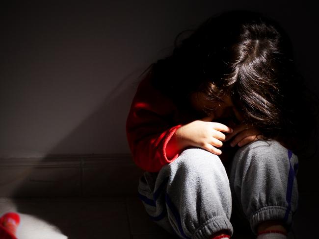 young girl sitting down alone in the dark.