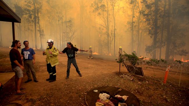 Firefighters hold back a blaze threatening a house at Tinonee near Taree. Picture: Nathan Edwards.