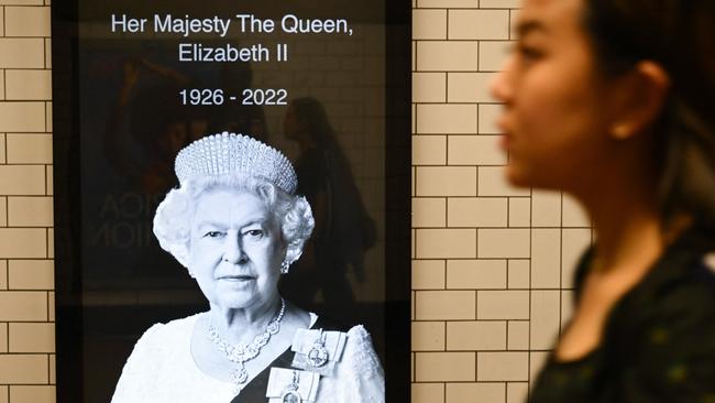 A woman passes by a picture of Britain's Queen Elizabeth II on the Underground in London. Picture: AFP