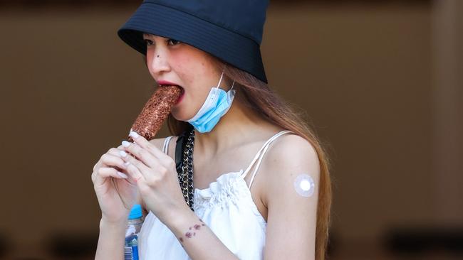 MELBOURNE, AUSTRALIA - NewsWire Photos 23 JANUARY 2022 : A woman has an ice cream after her booster vaccination at the Royal Exhibition Building as the omicron covid-19 variant spreads throughout Australia. Picture : NCA NewsWire / Ian Currie