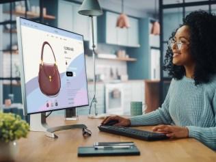 Latina Female Using Desktop Computer with Clothing Online Web Store to Choose and Buy Clothes from New Collection. Female Browsing the Internet at Home Living Room while Sitting at a Table