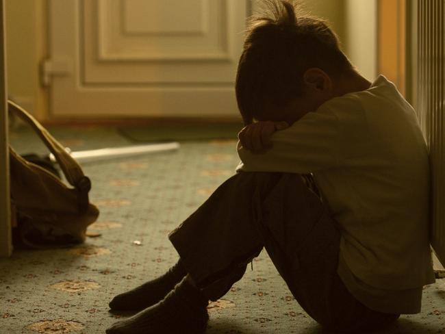 sad child with his head between his legs left alone at home iStock image