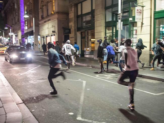 Youths ran down Flinders Lane as street battles continued through the night. Picture: Jake Nowakowski