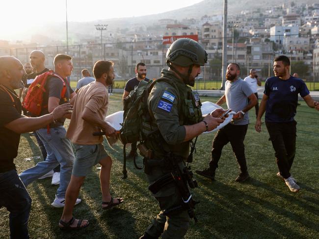 Israeli security forces and medics transport casualties from a site where a reported strike from Lebanon fell in Majdal Shams village. Picture: AFP