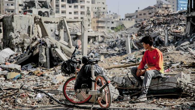 A Palestinian youth sits next to his bicycle amid the rubble of destroyed buildings in Gaza City. Picture: AFP.