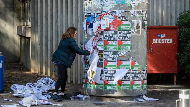 A woman tears down Gaza posters on her way to the a protest by Jewish Israel supporters near the University of Melbourne. Picture: Jason Edwards