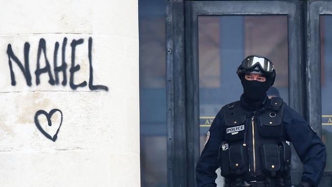 A French National police officer secures the entrance to a building as he stands next to the name 'Nahel', sprayed on a column during protests in Nantes. Picture: AFP