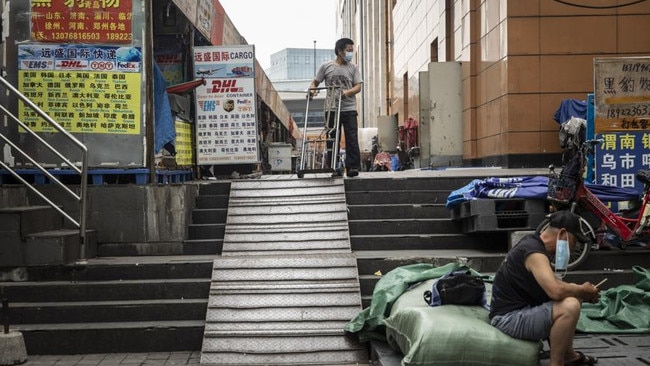 A porter wearing a protective mask stands outside of a wholesale mall in Guangzhou, China. Picture: Qilai Shen/Bloomberg