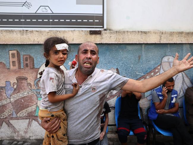 EDITORS NOTE: Graphic content / TOPSHOT - A Palestinian man reacts as he holds an injured girl following an Israeli airstrike on Rafah, in the southern Gaza Strip on October 17, 2023, amid the ongoing battles between Israel and the Palestinian group Hamas. Relief convoys which have been waiting for days in Egypt were on October 17, headed towards the Rafah border crossing with the besieged Palestinian enclave of Gaza, aid officials said, as thousands of people, both Israeli and Palestinians have died since October 7, 2023, after Palestinian Hamas militants based in the Gaza Strip, entered southern Israel in a surprise attack leading Israel to declare war on Hamas in Gaza on October 8. (Photo by MOHAMMED ABED / AFP)