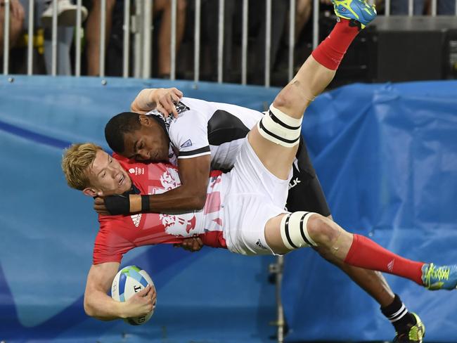 Britain's Mark Robertson (lower) is tackled by Fiji's Josua Tuisova in the men’s rugby sevens gold medal match between Fiji and Britain during the Rio 2016 Olympic Games at Deodoro Stadium in Rio de Janeiro on August 11, 2016. / AFP PHOTO / John MACDOUGALL