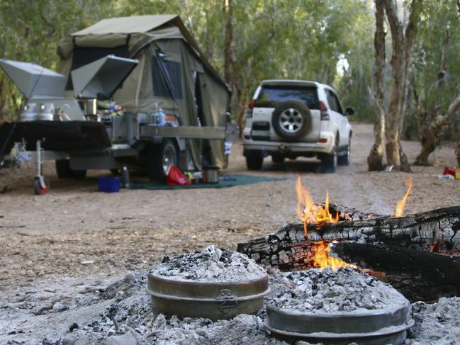 Undated : Istock - Remains of campfire in foreground and tent and 4wd in background.