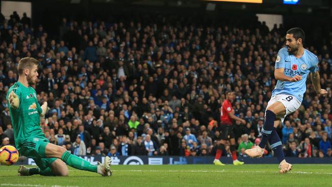 Manchester City midfielder Ilkay Gundogan slides the ball into the net past Manchester United goalkeeper David de Gea at Etihad Stadium. Picture: AFP