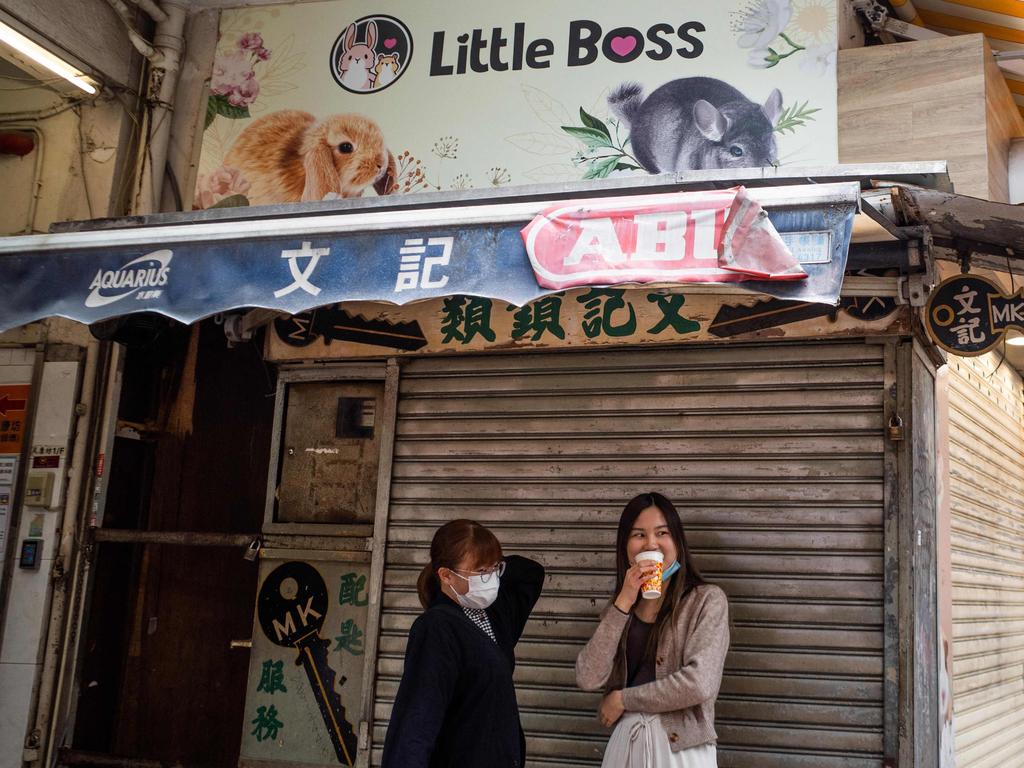 People stand under a banner for a pet shop where an employee and a customer later tested positive for Covid-19 after handling hamsters. Picture: AFP