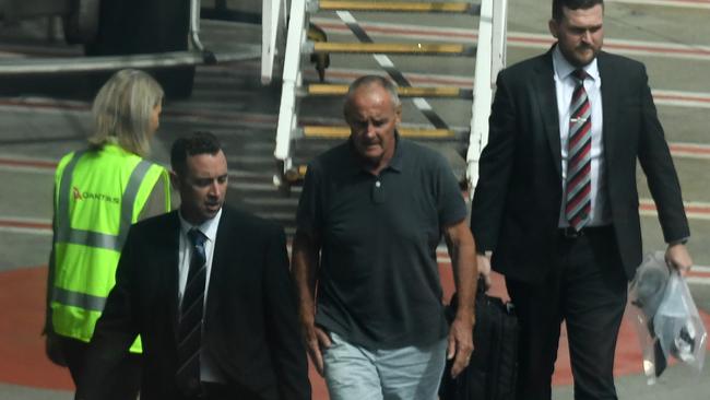 Chris Dawson, centre, is escorted by NSW Police detectives off a plane at Sydney airport as he is extradited from the Gold Coast following his arrest in December 2018.