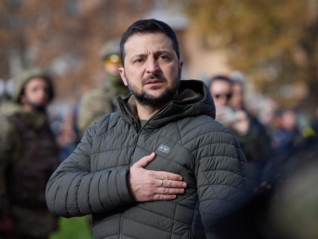 (FILES) This handout photograph taken and released by Ukrainian Presidential press service on November 14, 2022, shows Ukrainian President Volodymyr Zelensky taking part in the flag laying ceremony during his visit to the newly liberated city of Kherson, following the retreat of Russian forces from the strategic hub. - The Russian invasion of Ukraine, launched on February 24, 2022, was a transformative moment for the 44-year-old Ukrainian leader, one that catapulted him from embattled leader of a struggling European outlier to a global household name and standard-bearer of opposition to Putin. (Photo by Handout / UKRAINIAN PRESIDENTIAL PRESS SERVICE / AFP) / RESTRICTED TO EDITORIAL USE - MANDATORY CREDIT 