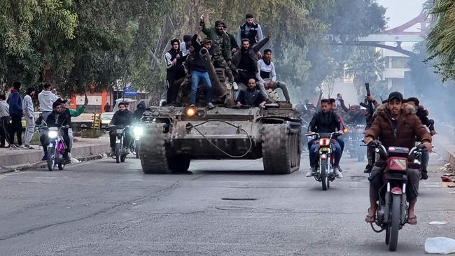 People ride a tank in the Syrian southern city of Daraa on Saturday after the collapse of government forces. Picture: Sam Hariri / AFP