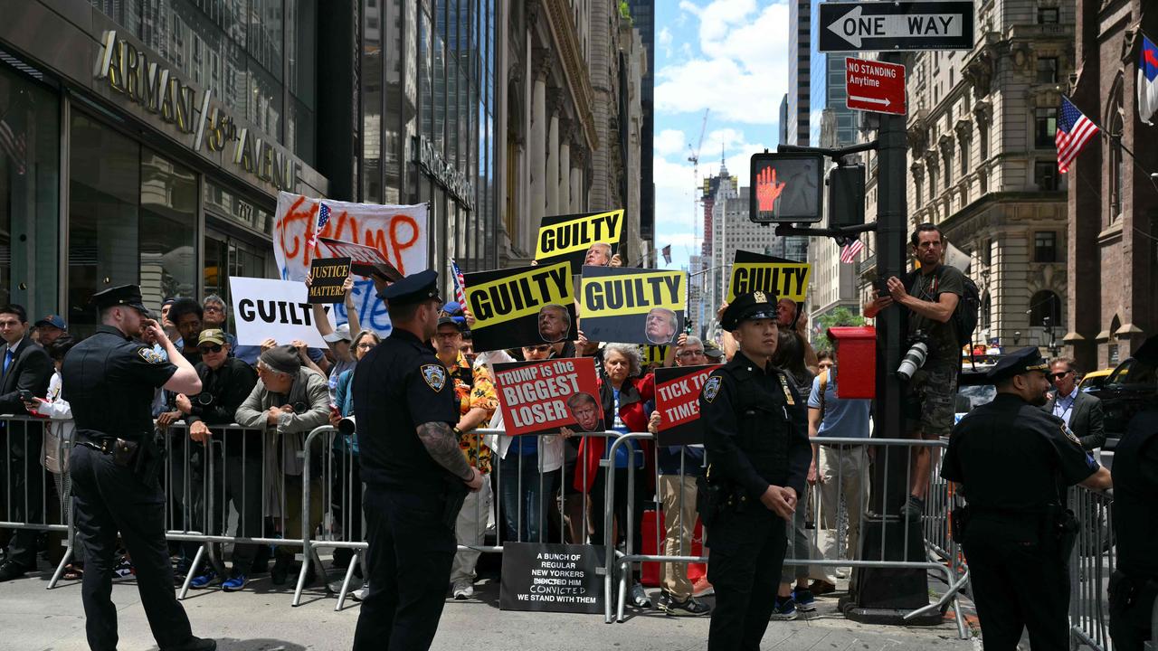 Protesters hold placards outside Trump Tower in New York City on May 31 before Trump speaks about his guilty verdict. Picture: Angela Weiss / AFP