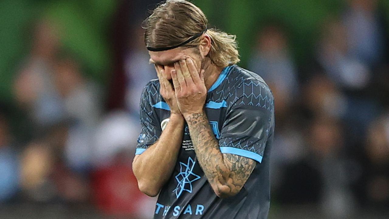 Luke Brattan of Sydney FC looks dejected as he leaves the field after being shown a red card