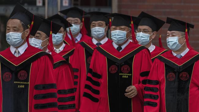 Members of the senior faculty from Renmin University of China arrive to the graduation ceremony at the school's campus.