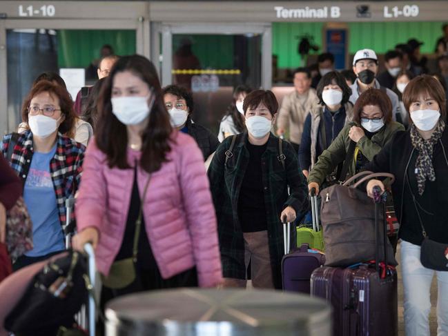 Passengers wear protective masks to protect against the spread of the coronavirus as they arrive on a flight from Asia, as COVID-19 spreads across the world. Picture: AFP