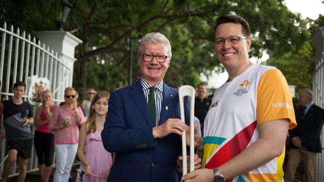 Queensland Governor Paul de Jersey passes the Commonwealth Games relay baton to swimming great Kieren Perkins in Brisbane yesterday.