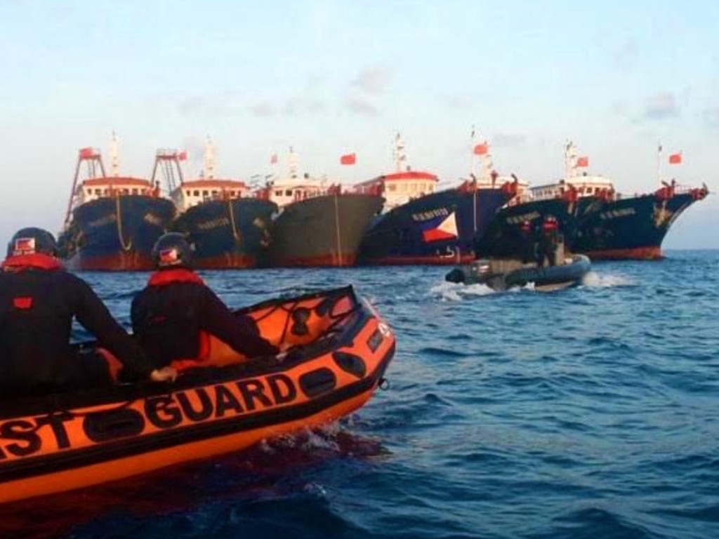 Philippine coast guard personnel patrol past Chinese vessels at Whitsun Reef, in the Spratly Islands. Picture: Philippine coast Guard (PCG) / AFP)