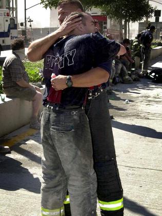 Emotional firefighters embrace after working among the rubble of the World Trade Centre. Picture: Nathan Edwards