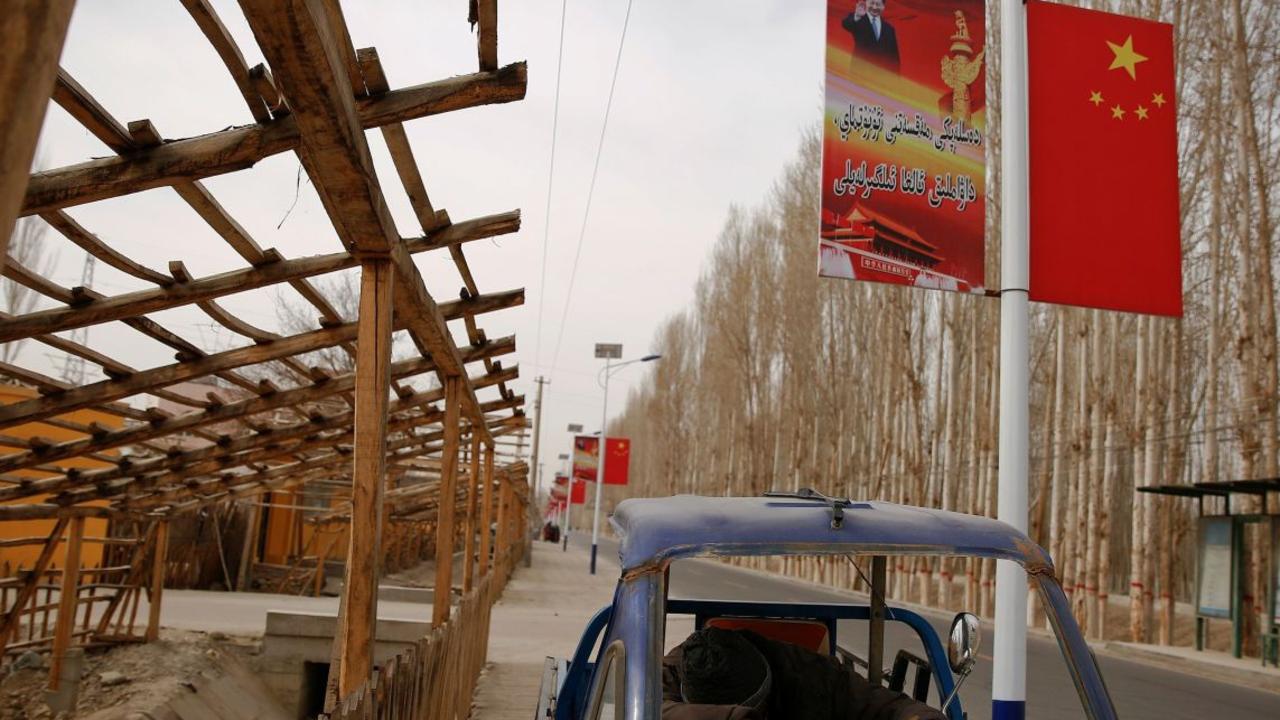 A poster showing Chinese President Xi Jinping lines a road in the Xinjiang Uighur Autonomous Region. Picture: Thomas Peter/Reuters