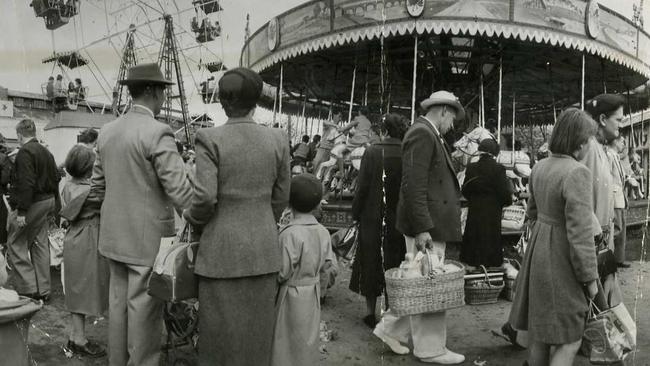 Circa 1950s — People walk past the Ferris wheel and merry-go-round.