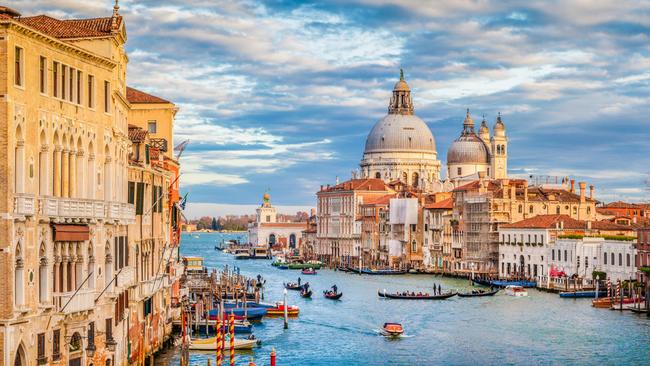 Venice’s famous Canal Grande with Basilica di Santa Maria della Salute in beautiful golden evening light at sunset.