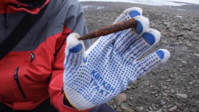 A scientist holds a rusted World War II bullet found on the frozen rocky ground. Picture: Ruptly