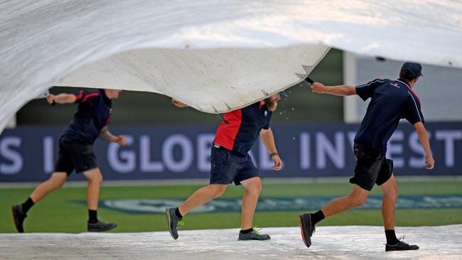 Ground staff take the covers off the pitch after rain on day four. Picture: AAP.